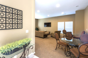 carpeted living room with tan walls, tan carpet, tables