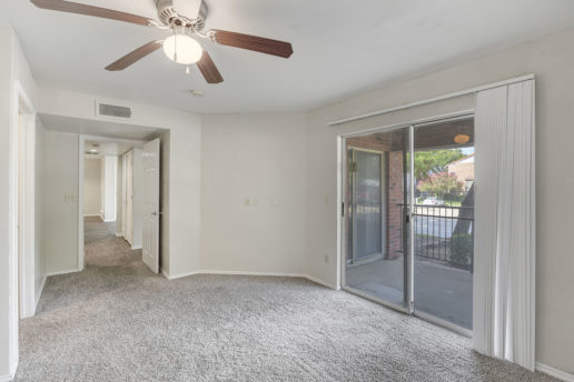 large carpeted room with ceiling fan and sliding glass door